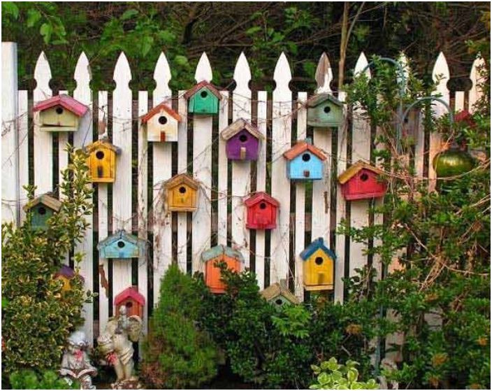 Ограда, украсена с дървени къщички за птици.