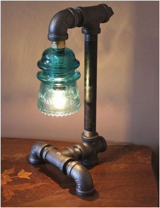 Une lampe personnalisée complexe fabriquée à la main à partir de vieux tuyaux et d'un isolant en verre électrique.