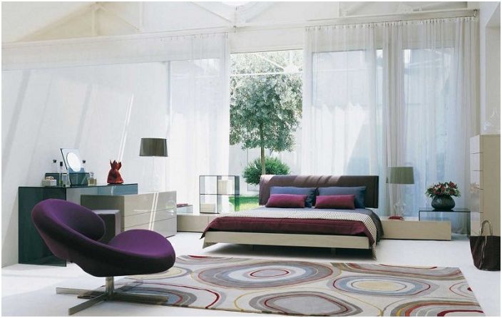 The bedroom is decorated with a carpet with cute circles and bright cushions on the sofa.