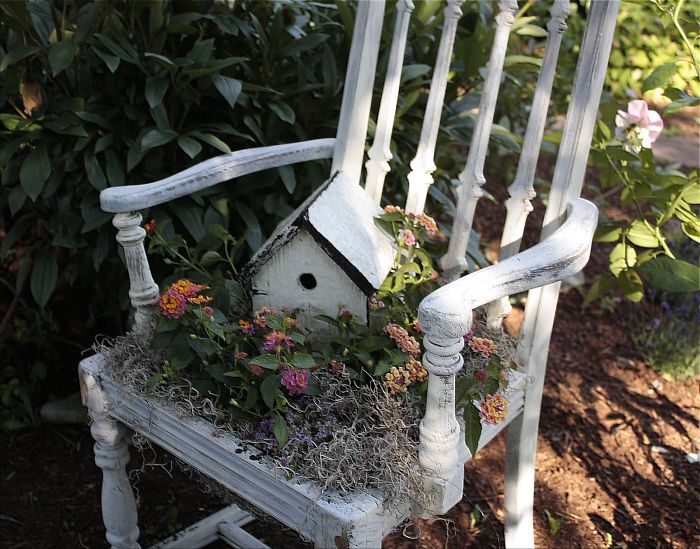 En vakker antikk stol med blomsterbed på toppen er en original løsning for hagen.