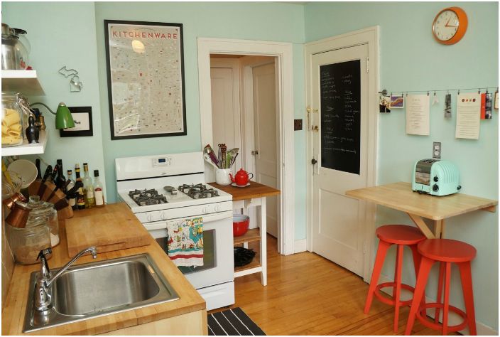 Malá kuchyň ve stylové mátové barvě s kompaktním dřevěným nábytkem.