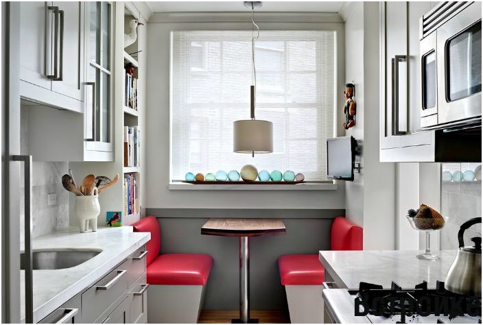 Egy keskeny téglalap alakú konyha, kompakt étkezőasztallal, sok dekoratív elemmel díszítve.