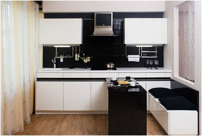 Маленькая кухня, выполненная в черно-белом цвете, с выдвижным обеденным столом.