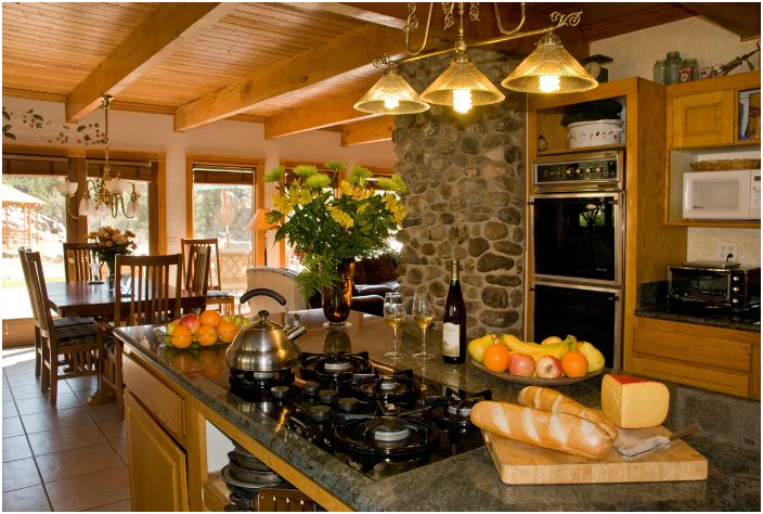 Уютна селска кухня с мебели от дърво и каменни стени.