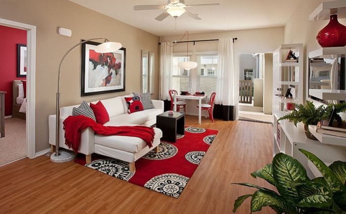 Living room with red accents by Borden Interiors & Associates