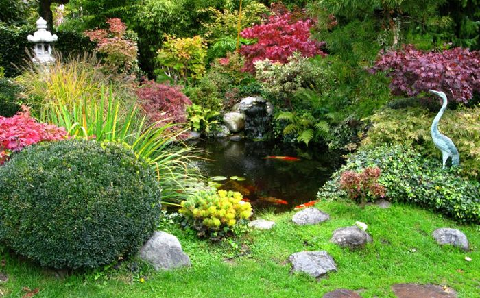 Japonská zahrada s kamennou lucernou a volavkou na pobřeží.
