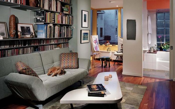 Ett oregelbundet format litet bord och bokhyllor skapar en konstnärlig interiör i ett litet vardagsrum.