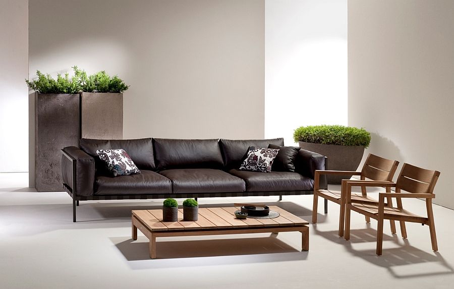 Дълъг кожен диван, дървени фотьойли и маса в хола